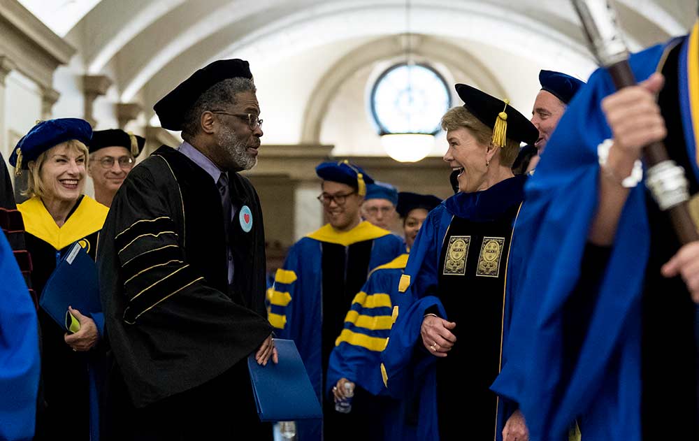 Sarah Mangelsdorf talks and laughs with Wade Norwood as the procession in academic attire leaves Eastman Theatre