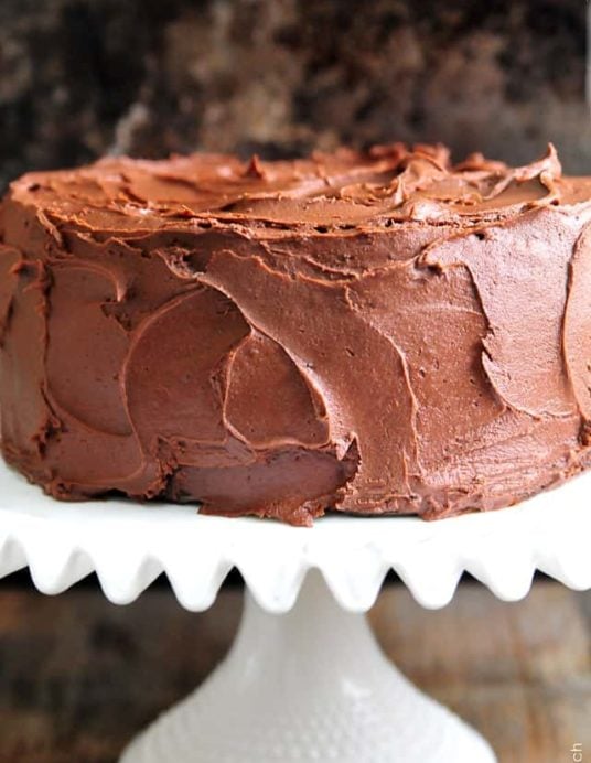 Amazing chocolate cake photographed with rich chocolate buttercream frosting on a white cake stand // addapinch.com