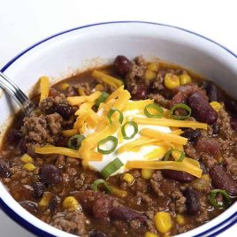 Taco Soup in a white bowl topped with sour cream, cheese, and green onions. #tacosoup #kidfriendly