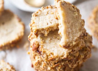 Close up image of a stack of pecan sandies rimmed in chopped pecans.