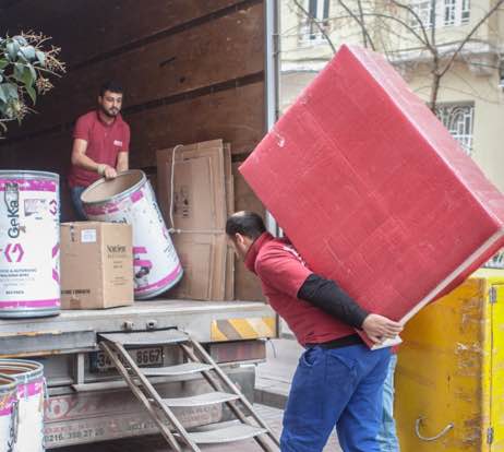 Kırmızı tişörtlü iki nakliyeci evden eve nakliye hizmeti verdikleri müşterilerinin eşyalarını nakliye kamyonuna taşıyor