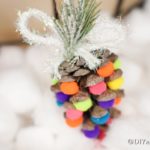 Up close picture of a colorful pinecone ornament against white cotton balls