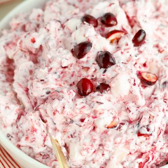 Creamy cranberry salad in a white bowl with a gold spoon.