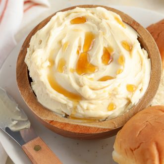 Maple butter in a brown bowl drizzled with maple syrup.