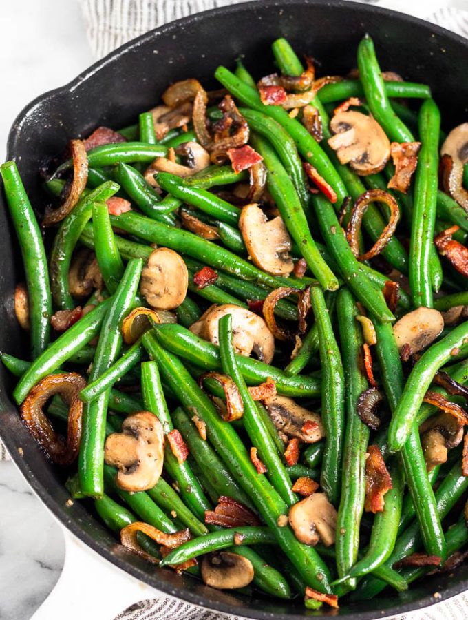 Cast iron skillet with green beans with mushrooms and onions.