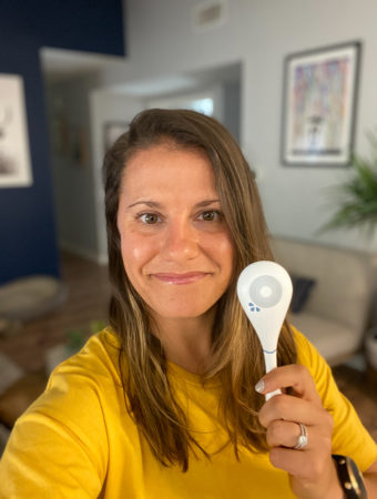 Girl in a yellow shirt with brown hair taking a selfie holding a Dasys Fertility Tracker.
