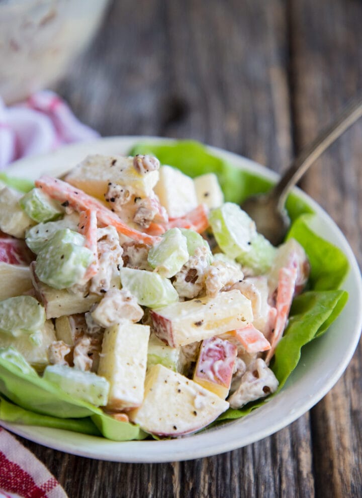 A bowl of Waldorf salad in a bowl with a fork and lettuce