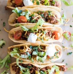 Taco meat in shells topped with lettuce, cheese, tomatoes and sour cream.