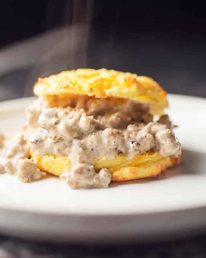 a low carb cheddar biscuit with sausage gray on a white plate