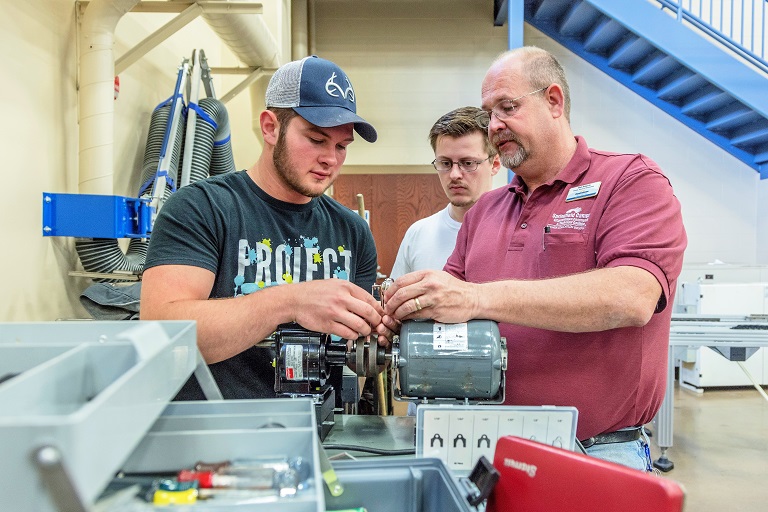 three men working on machine in shop setting