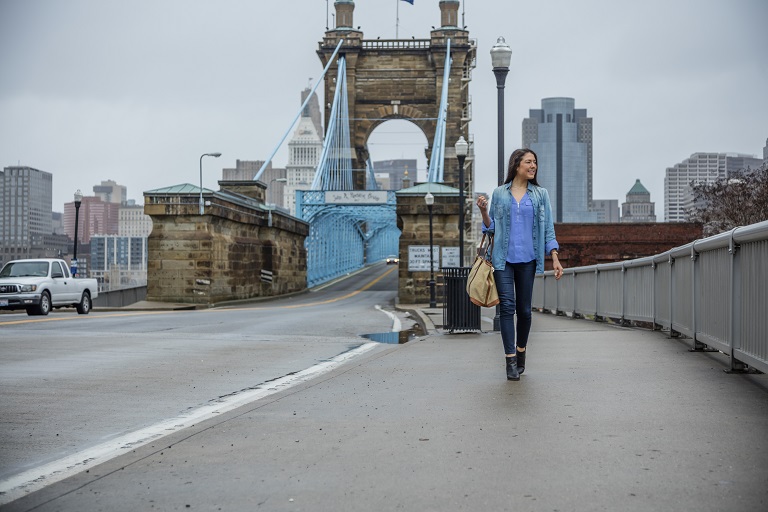 woman walking in front of northern kentucky bridge