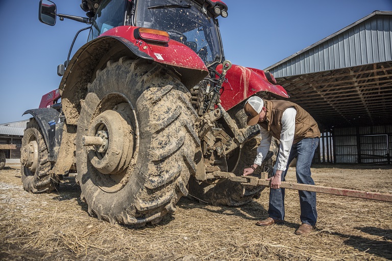 male student working outside fixing a tractor