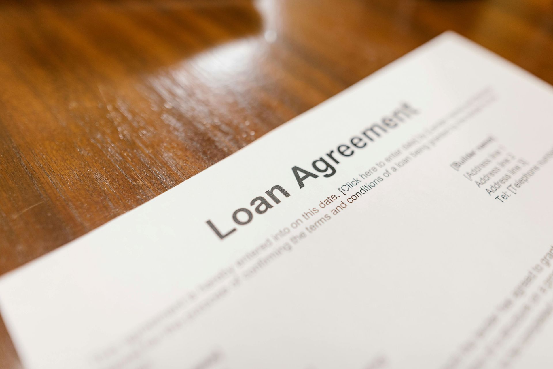 A loan agreement document placed on a wooden table, signifying mortgage contract agreement.