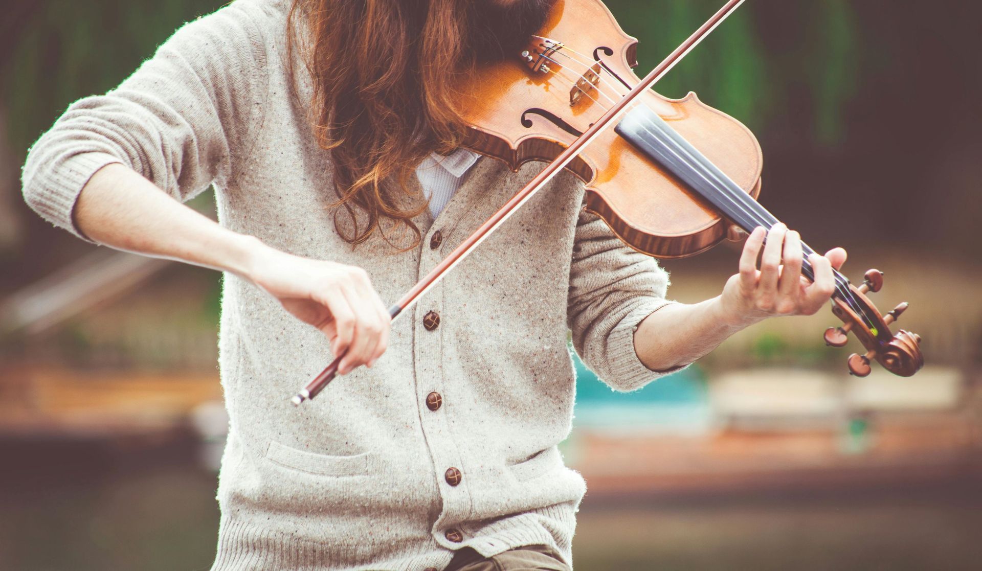 A woman with long hair skillfully playing a violin, immersed in the music.