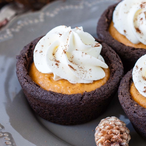 Satisfy your Fall cravings with these easy Pumpkin Spice Cookie Cups! Chewy chocolate cookie cups filled with pumpkin pudding and topped with whipped cream. | livforcake.com