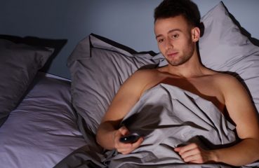 Young man in bed with remote