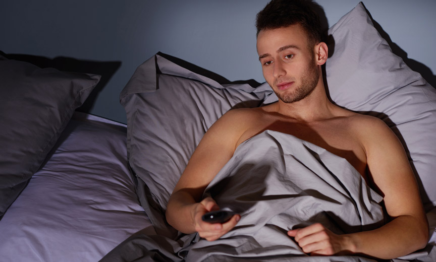 Young man in bed with remote