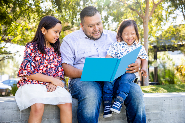 A father reads a book to his two children.