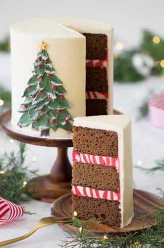 A photo of a gingerbread cake with a painted Christmas tree made from butter cream on the front.