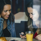 two female mixed race friends having a coffee and chatting