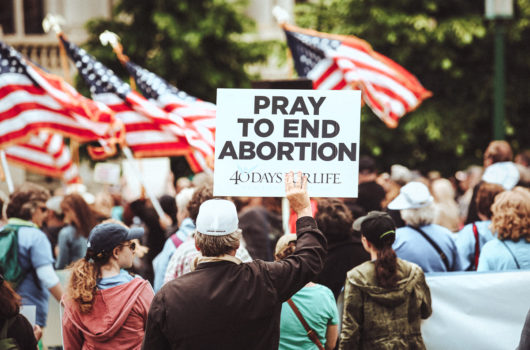[Photo: Anti-choice supporters hold signs and flags as they rally.]