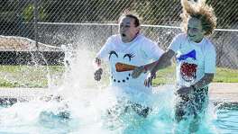 Karen Dahle gasps as she hits the frigid 55-degree water in the pool at Wendy Swan Memorial Park in Schertz on Saturday morning with her son Ryan Murray, 10, right. Son Tyler Murray, 12, was already underwater (at left) during the third annual Polar Bear Plunge for YMCA.