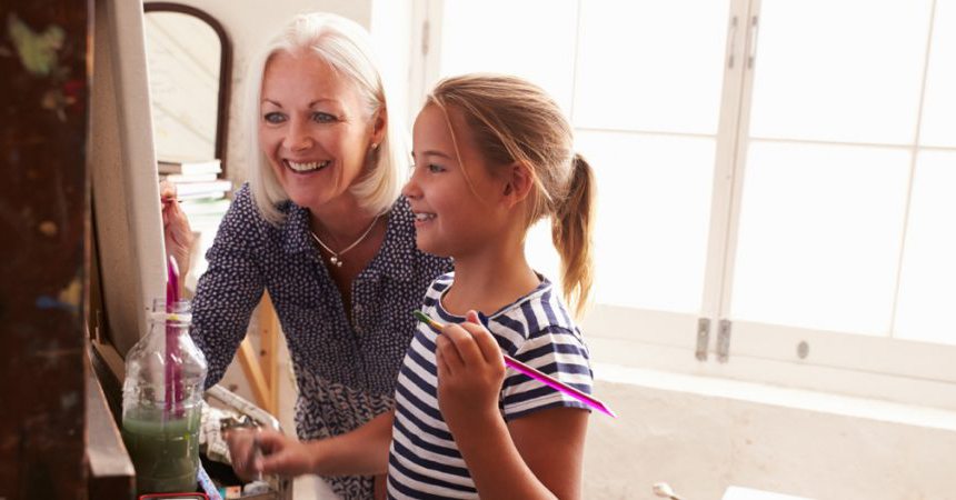 Grandmother and granddaughter painting a picture while smiling