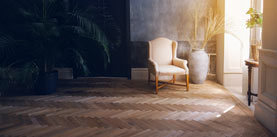 A beige armchair and a blue vase stand by the window in the living room, next to a large palm tree.