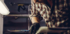 Ski maintenence. Removing excess wax from race ski base plastic scraper. Ski service and repair. Winter shop worker doing base repair. Rental workshop service. Repairman In Workshop Ski Service