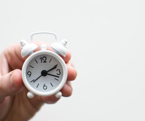 Hand holding a small alarm clock