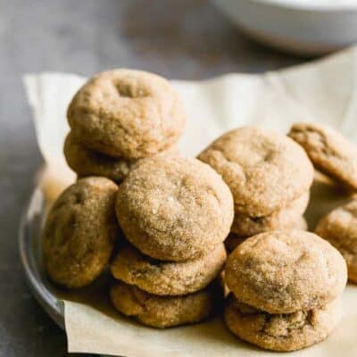 A stack of molasses cookies on a plate lined with parchment paper.