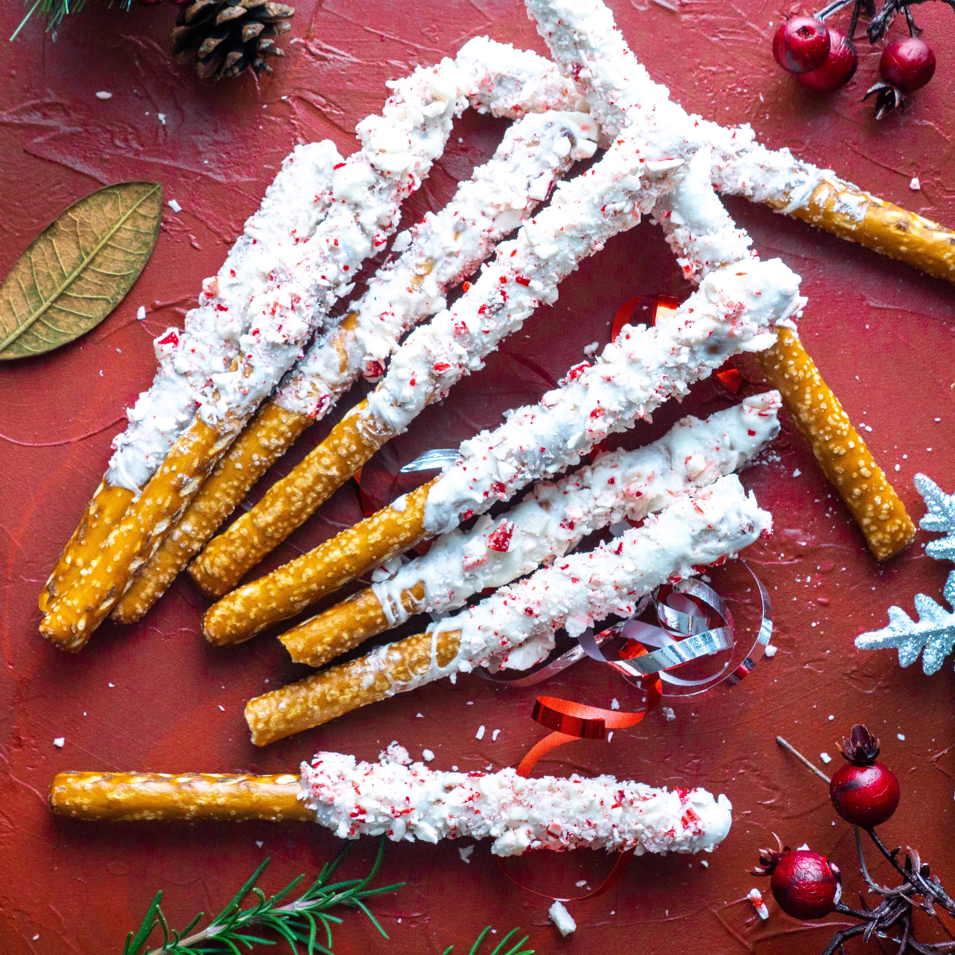 peppermint bark pretzels on red backdrop with holiday decorations