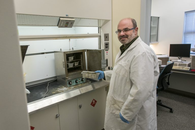 Christopher Perkins &rsquo;89 (CAHNR) '95 MS, puts trays of hemp into a drying machine at UConn's Center for Environmental Sciences and Engineering lab. (Sean Flynn/UConn Photo)