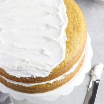 Overhead view of vanilla cake partially topped with vegan buttercream frosting.