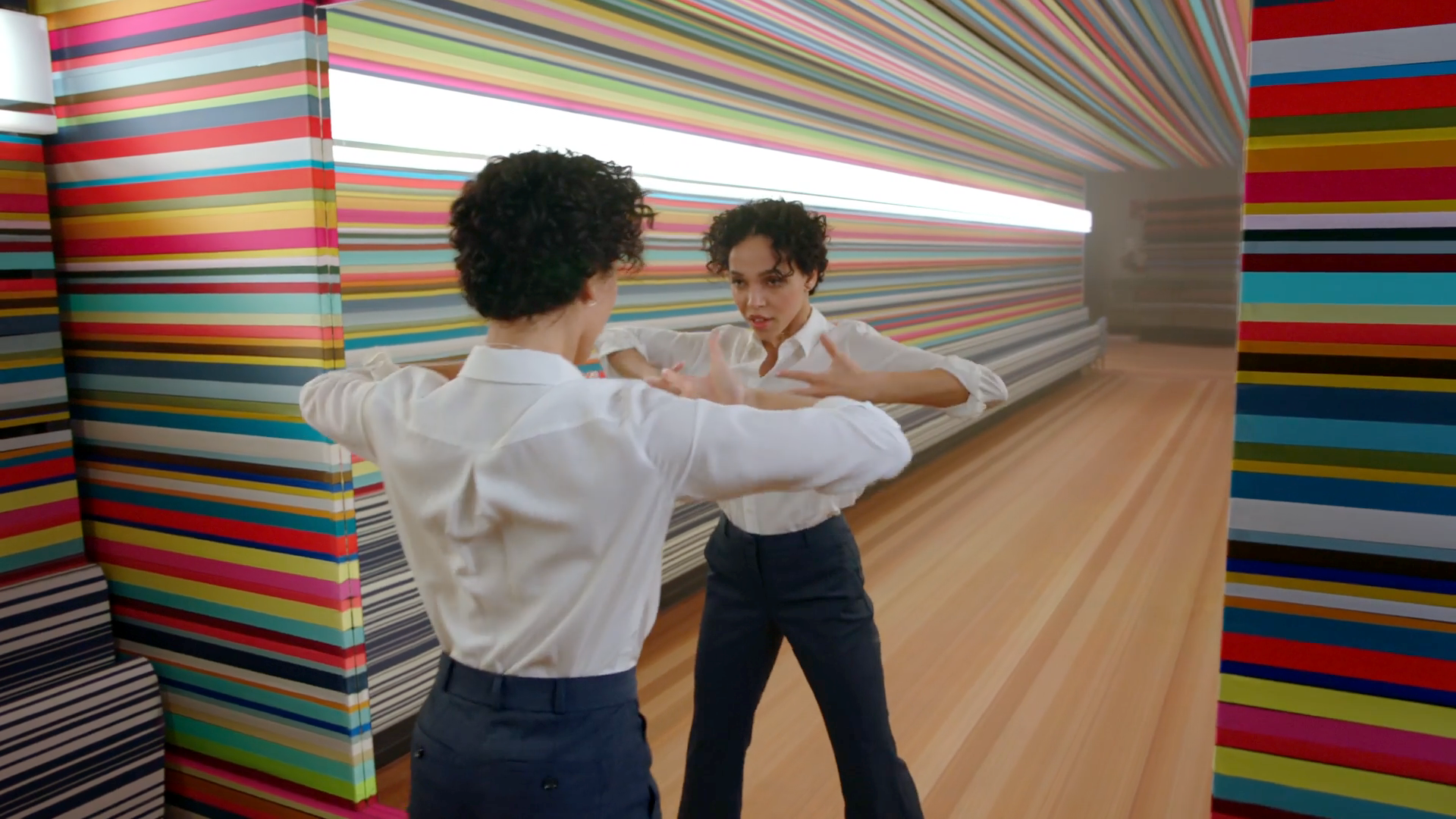 Fk Twigs looking into a mirror with rainbow walls