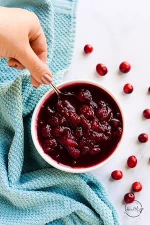 hand serving easy homemade cranberry sauce with a spoon
