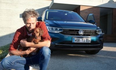 Tiguan R-Line stoj&iacute;c&iacute; u domu, s mužem drž&iacute;c&iacute;m psa