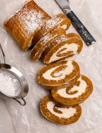 An overhead shot of sliced pumpkin roll with pieces laying cut-side down.