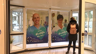 Eine Drehtür in einem Krankenhaus, auf der Werbung zu sehen ist.