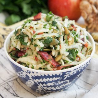 Apple celeriac salad in small bowl in front of some of ingredients