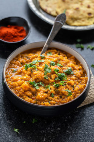 mashed butternut squash in a bowl with some flatbreads placed in the background
