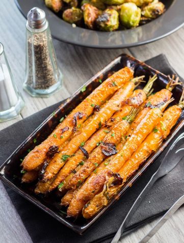 Buttery Balsamic Garlic Roasted Carrots on a serving dish sprinkled with parsley