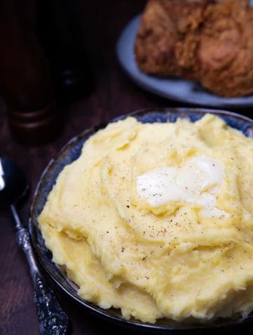 A big bowl of mashed potatoes with butter melting on top