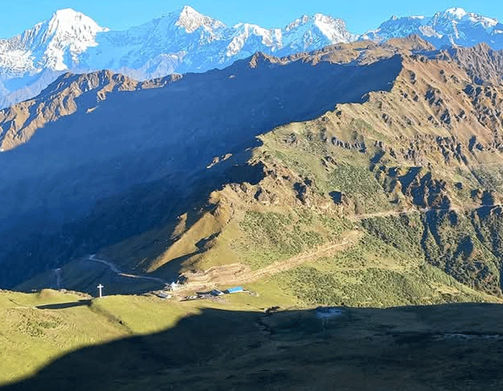 "A scenic view of Rubi Valley Trek featuring lush green hills, rugged trails, and a distant mountain range under a clear sky."