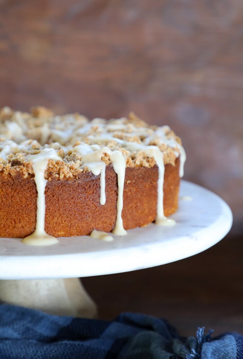 keto pumpkin chai coffee cake on a white pedestal with a blue napkin below it