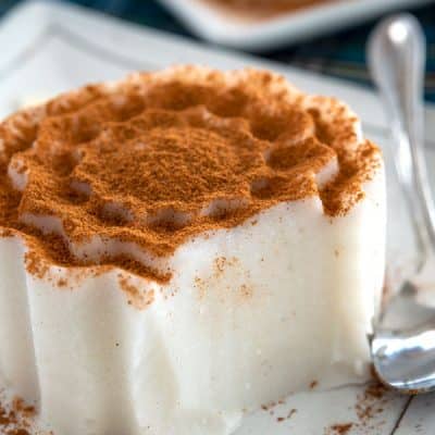 Individual tembleque serving on plate with a bite missing