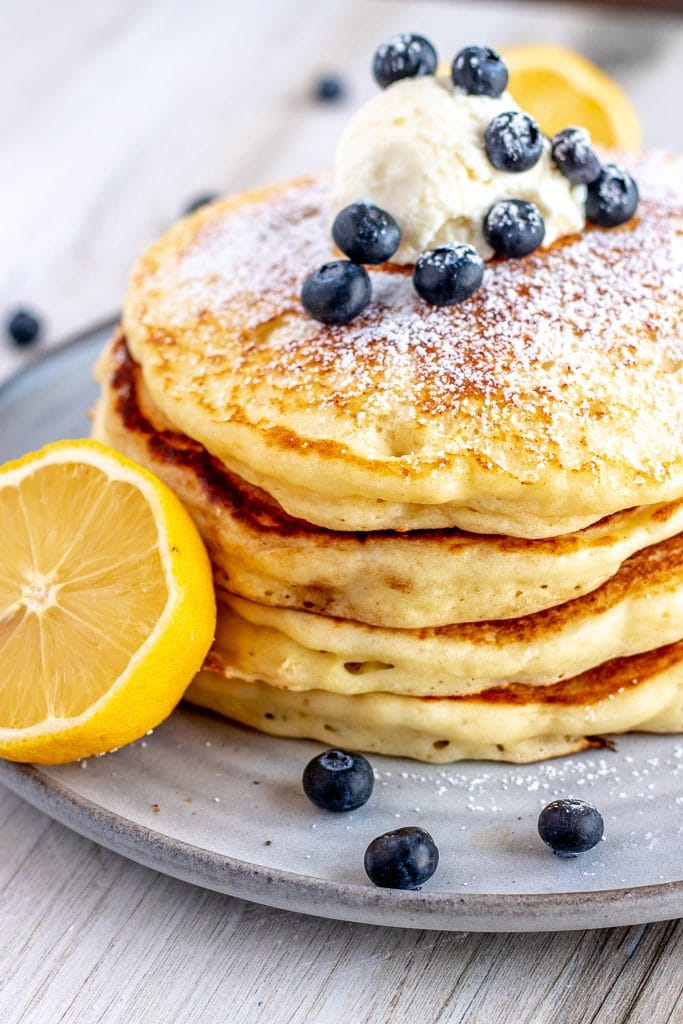 stack of pancakes with a cut lemon, ricotta and blueberries