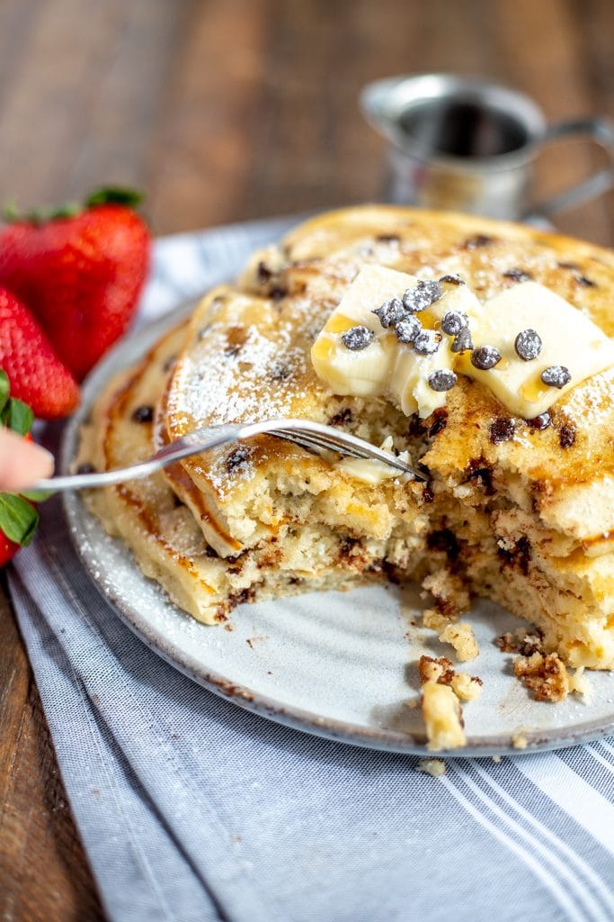 chocolate chip pancake stack with strawberries and a fork