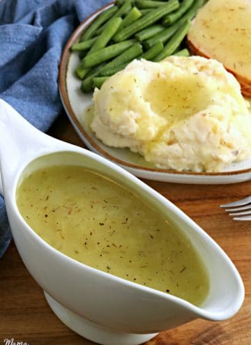 gluten-free gravy in a white gravy boat with a plate of dinner food in the background