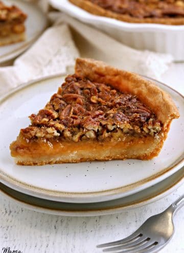 slice of gluten-free pecan pie on a white plate with a fork and the pie in the background